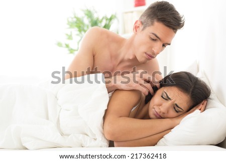 Beautiful young boyfriend waking his cute sleepy girlfriends  in bed in the morning.