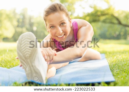 Cute girl doing stretching exercises in the park.