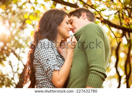 Young heterosexual couple in love in the park, photographed at the moment while the girl pulls the boy to kiss him.