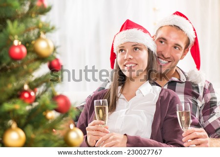 Young beautiful couple Celebrating Christmas or New Year with glass of champagne.