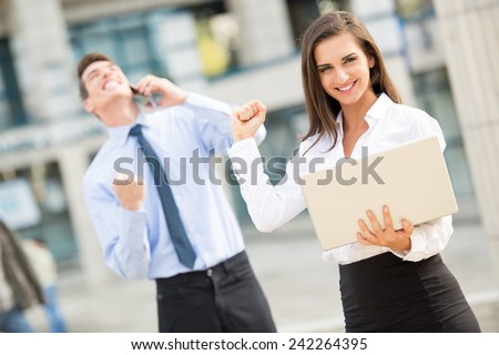 Young business couple standing in front of office buildings caught in the moment of joy for the successful completion of the job.