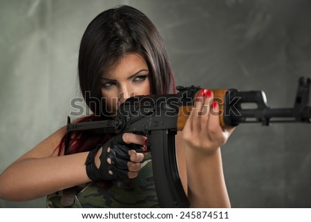 Young beautiful military woman holding rifle and take aim. Ready to shoot.