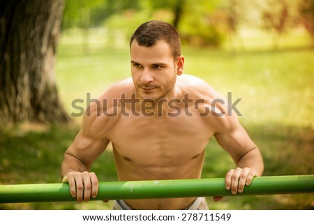 Young muscle Man doing vertical push-ups in the park.