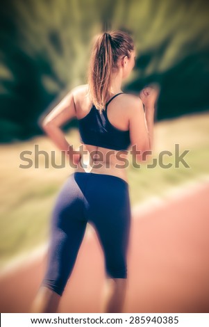 Beautiful girl jogging on the tartan track. Rear view.