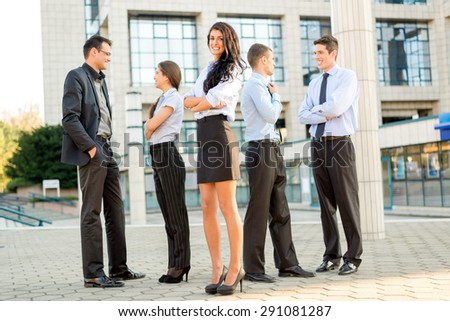 Cute young businesswoman with her team young business people standing in front of office building.