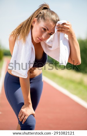 Beautiful young woman resting after jogging and wipes the sweat with towel.