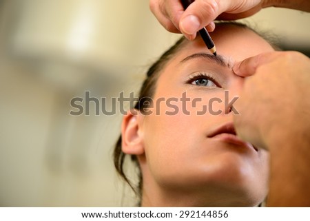 A pretty woman having eyebrow make-up applied by a makeup artist. Close up.