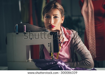 Beautiful tired woman sits in front of the sewing machine and thinking. Looking at camera. Vintage concept.