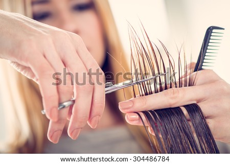 Close-up of a hairdresser cutting the hair of a woman. Selective focus.