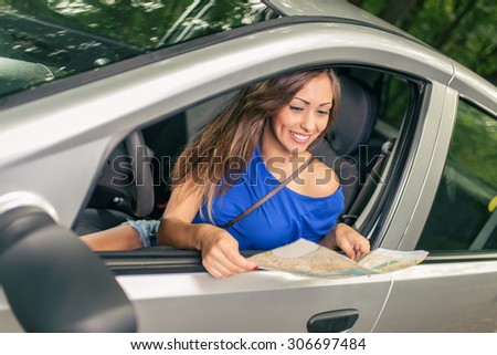 Young beautiful woman sitting in car and looking at a map.