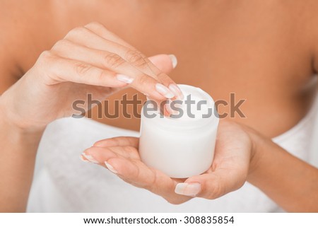 Close-up of moisturizing face cream in the hands of a young woman, unrecognizable face with a underwear. Selective focus.