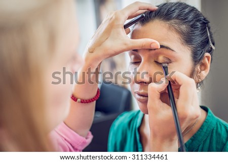 Make-up artist applying the eyeshadow to model. Close up.
