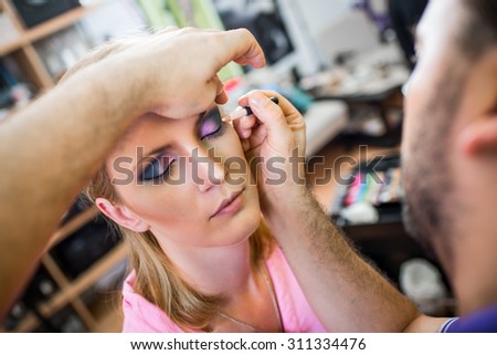 Close up of a make-up man artist getting eyeliner to model.