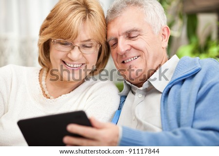 Happy senior couple using tablet PC at home