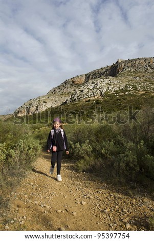 Young girl walking along mountain path