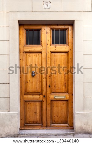 A classic double wooden door with a knocker and two little grilled windows on the upper part. The picture has been taken in the SarriÃ?Â  quarter of Barcelona, where old wooden doors are still typical.