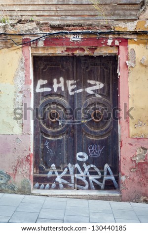 An abandoned building, formerly a restaurant. It\'s double door entrance is closed down with a chain and a lock, and covered in graffiti. Shot at the SarriÃ?Â  quarter of Barcelona (Spain).