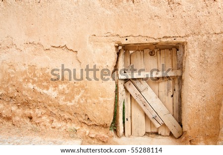 A rustic door, made of wood boards, on a wall made of adobe (clay and straws). The photo was taken at one of the many small villages of the province of Soria, Spain (Europe).