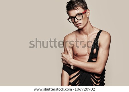 the guy in glasses in the studio with a beautiful figure, a portrait of a guy. Light, bright and fashionable photos for the magazine