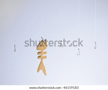 Wooden fish caught on one hook among other empty ones