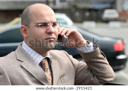 A businessman calling by mobile phone, around a luxurious car