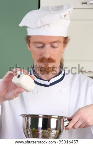 Young chef add salt in the pot, preparing lunch