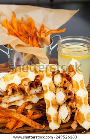 Deep fried chicken breast tenders, bacon and cheese in a golden waffle sandwich with sweet potato fries and lemonade on the side