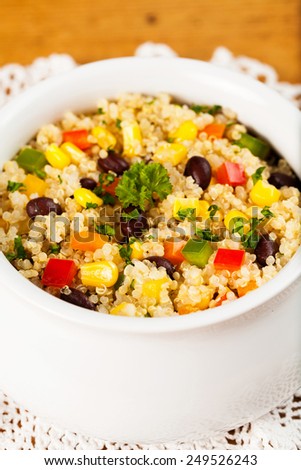 A bowl of healthy quinoa salad with black beans, tomato, corn, parsley and red and green bell peppers