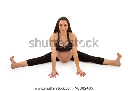 A beautiful pregnant woman in a forward fold yoga pose