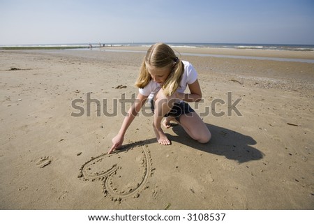 puppy love, girl drawing a heart in the sand at the beach