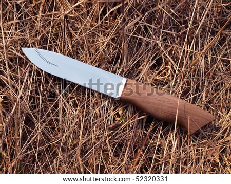 The Finnish knife with the wooden handle on a background of a dry grass