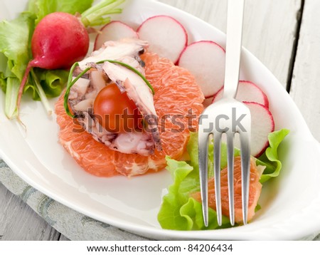 octopus carpaccio over slice grapefruit with radish and lettuce