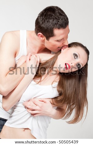 Portrait of young loving couple. Man embracing and biting passionate woman.