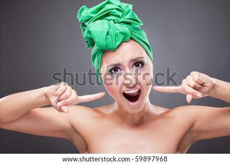 Irritated young woman with green scarf on head and bright pink-green makeup shouting