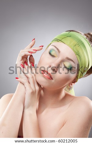 Dreaming young beautiful woman with green makeup holding hands near neck