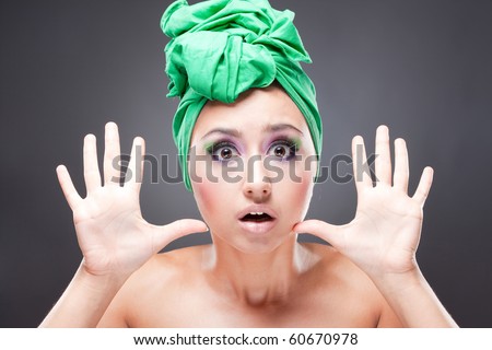 Scared woman with green scarf on head and bright pink-green makeup rejecting