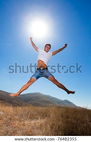 Happy young man jump in the mountains looking at camera