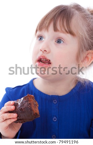Surprised little girl eating chocolate cake looking up