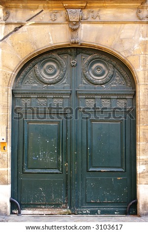 Grunge painted wooden door with bronze handles in Paris
