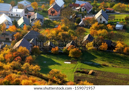 Aerial view on small town - colorful fields and trees in autumn,