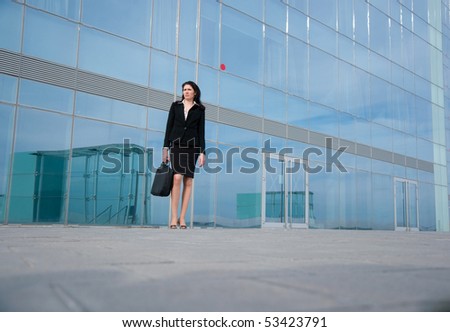 Business woman posing with a laptop\'s bag in a front of modern office building