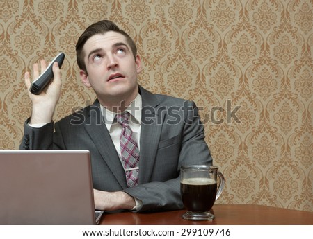 Young business man in a suite and tie with a cup of black coffee on a phone call with a laptop