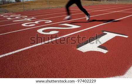A lone female runner on a ruberized track at the start/finish line