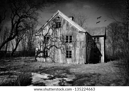 Old dilapidated house in black and white with scary shadows and trees, textured effect.