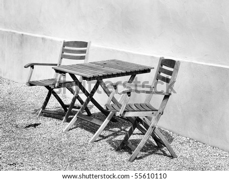 Black and white picture of garden chairs and a table.