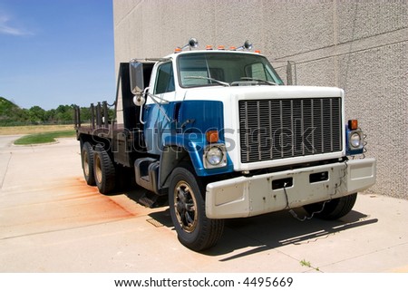 This is a mid 1980\'s heavy duty flatbed truck viewed from the front corner.