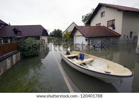 Flooded house after heavy rain with motor boat on the street.