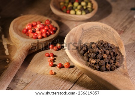 Top view of wooden spoon full of mixed colorful peppercorns