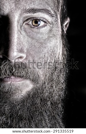 Picture with half face of a peaceful man with beard.