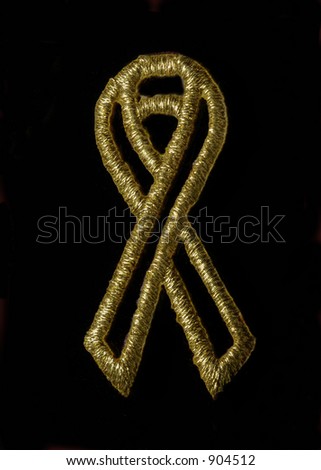 The cure ribbon logo--gold-colored metallic on a black background.  This logo has been placed in the public domain by Carol Sutton